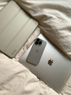 an apple laptop computer sitting on top of a bed next to a white ipad case