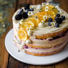 a cake with lemons, blueberries and blackberries is on a white plate