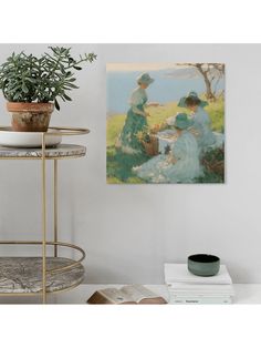 two women sitting at a table in front of a painting on the wall next to a potted plant