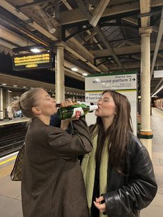 two women are drinking beer at the train station