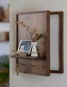 a wooden shelf with a mirror and vase on it, next to a potted plant