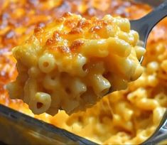 a spoon full of macaroni and cheese being lifted from a casserole dish