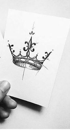 two cards with designs on them are being held by someone's hand and the one has a crown drawn on it