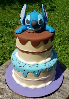 a three tiered cake decorated with fondant and frosting, including an animal on top