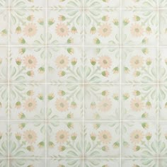 a white tiled wall with pink and green flowers painted on the tiles in different colors