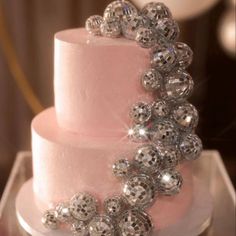 a three tiered pink cake with silver balls on top