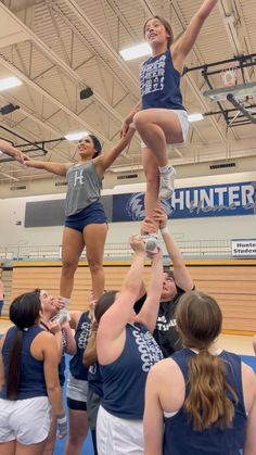 the cheerleaders are doing tricks for the team in the gym as they stand on top of each other