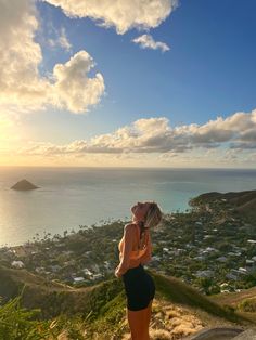 a woman standing on top of a hill next to the ocean