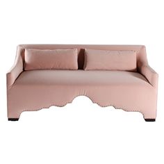 a pink couch with scalloped edges and pillows on it's back end