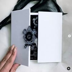 a person is opening up a white box with a black and silver design on it