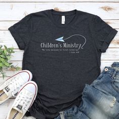 Children's Ministry T-Shirt, Kids Ministry, Kids Min, Children's Pastor, Volunteer Appreciation, Leader Shirts, Bible Verse shirt This classic unisex jersey short sleeve tee fits like a well-loved favorite. Soft cotton and quality print make users fall in love with it over and over again. These t-shirts have-ribbed knit collars to bolster shaping. The shoulders have taping for better fit over time. Dual side seams hold the garment's shape for longer.  .: 100% Airlume combed and ringspun cotton (fiber content may vary for different colors) .: Light fabric (4.2 oz/yd² (142 g/m .: Retail fit .: Tear away label .: Runs true to size Childrens Ministry Director, Volunteer Tshirt, Nursery Christmas, Sunday School Projects, God Clothes, Church Nursery, Volunteer Appreciation, Kids Ministry, Bible Verse Shirt