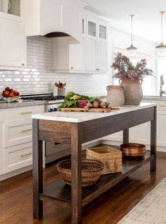 a kitchen with white cabinets and wooden flooring next to an island in the middle