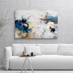 a living room with a white couch and large painting on the wall above it's coffee table