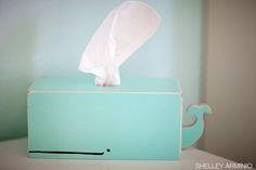 a tissue dispenser sitting on top of a table next to a blue box