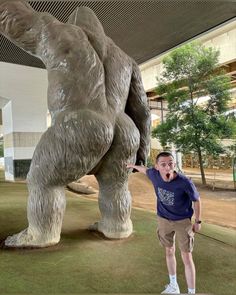 a man standing in front of a statue of a large bear with his mouth open