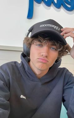 a young man with headphones on his ears sitting in front of a pepsi sign