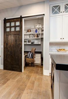 an open door leading to a kitchen with white cabinets and wood floors, along with a wooden floor