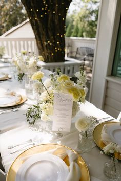 the table is set with white and yellow plates, silverware, and centerpieces