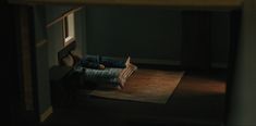 a person laying on top of a bed in a room next to a window at night