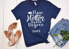 Graduation shirt, Hotter by one Degree- tshirt graduation gift 2023, Funny graduate shirt, Bachelors, masters, gift for grads This classic unisex jersey short sleeve tee fits like a well-loved favorite. Soft cotton and quality print make users fall in love with it over and over again. These t-shirts have-ribbed knit collars to bolster shaping. The shoulders have taping for better fit over time. Dual side seams hold the garment's shape for longer.  .: 100% Airlume combed and ringspun cotton (fibe Pre-shrunk Cotton T-shirt For Graduation Party, Graduation T-shirt With Letter Print In Relaxed Fit, Cotton T-shirt With Letter Print For Graduation Party, Casual Shirt With Custom Print For Graduation, School Spirit Cotton T-shirt For Graduation Gift, Cotton Graduation T-shirt, Cotton T-shirt For Graduation Party, Casual Custom Print T-shirt For Graduation, Cotton Short Sleeve T-shirt For Graduation Party