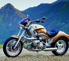 a motorcycle parked on the side of a dirt road in front of a mountain range