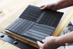 a person is cutting out black tiles on a table