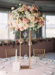 an elegant centerpiece with pink and white flowers sits on top of a round table