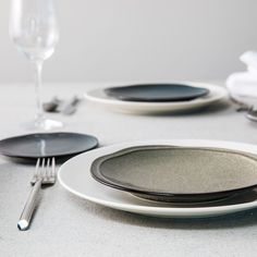 the table is set with black and white plates, silverware, and wine glasses