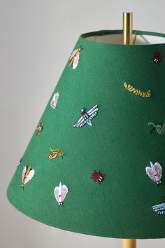 a green lampshade with stickers on it and a gold lamp holder in the middle