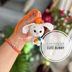 a hand holding a small crocheted bunny with an orange ribbon around it's neck