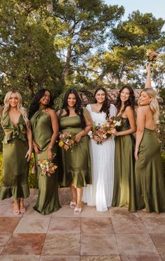 a group of women standing next to each other wearing dresses and holding bouquets in their hands