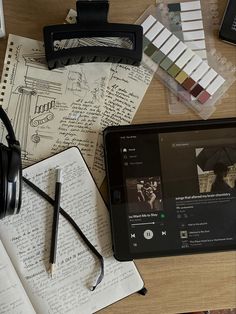 an ipad and headphones sitting on top of a wooden table next to some books