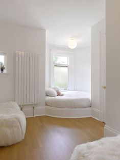 a bedroom with white walls and wood floors