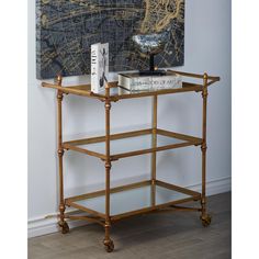 a wooden shelf with books on it in front of a painting and a wall mounted map