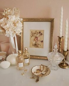 a table topped with lots of vases and candles next to a framed painting on the wall