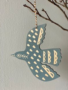 a blue bird hanging from a tree branch with the initials bb and b on it