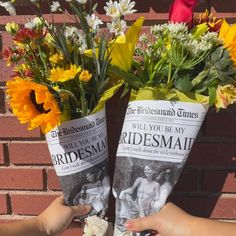 two people holding flowers in front of a brick wall with an ad for bridesmaid on it