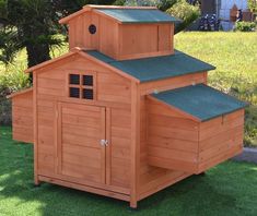 a wooden chicken coop with green roof and shingles on the top, sitting in grass