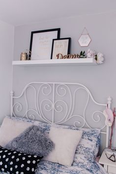 a white metal headboard with pillows and pictures on it's shelf above the bed