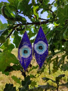 blue beaded eye earrings hanging from a tree branch