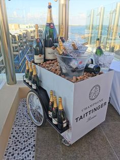 a cart filled with bottles of wine on top of a floor next to a window