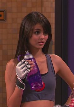 the girl is wearing gloves and holding a purple water bottle in her hand while standing next to another woman