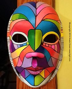 a colorful mask hanging on a wooden door