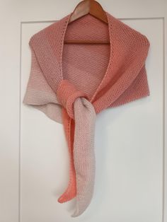 a pink sweater hanging on a white wall