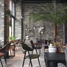 an empty restaurant with chairs and tables in front of a brick wall filled with potted plants