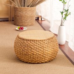 a basket sitting on top of a wooden floor next to a vase