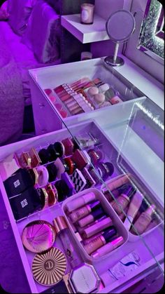 an assortment of cosmetics and makeup products on display in a purple lit room with a mirror