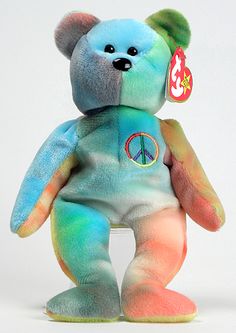 a blue and green teddy bear with peace sign on it's chest, sitting upright