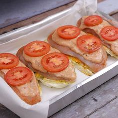 there are several sandwiches with tomatoes on them in a tin tray, ready to be eaten