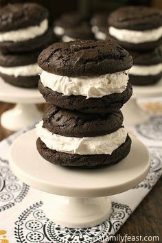 chocolate cookies with whipped cream on top are stacked on a cake plate and ready to be eaten